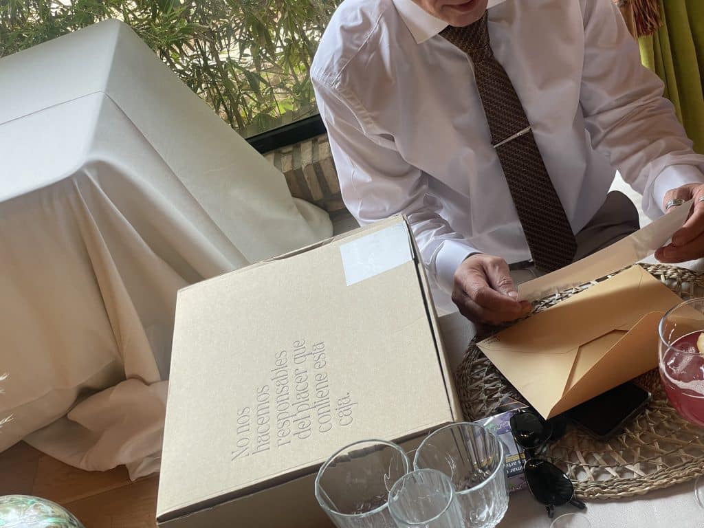 "Hombre abriendo una caja regalo gourmet con ilusión, descubriendo productos artesanales en su interior